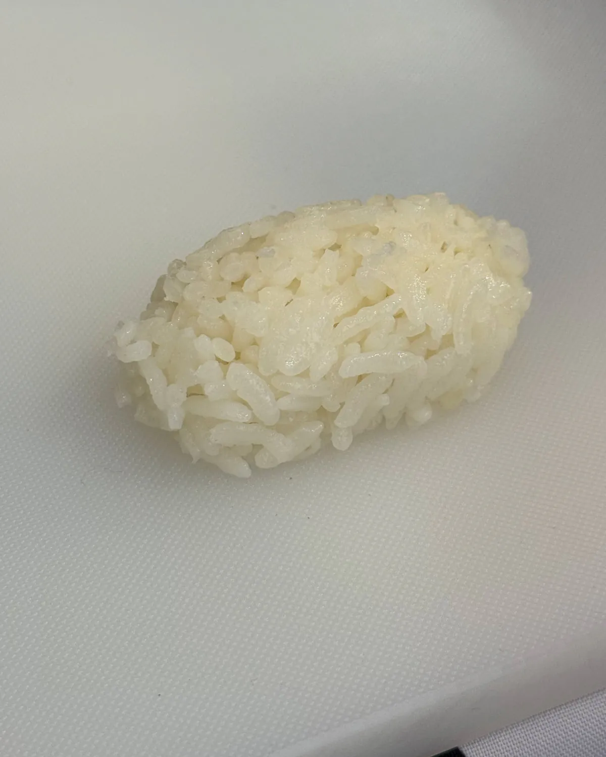 A chef's gloved hand pressing warm rice onto a sheet of nori