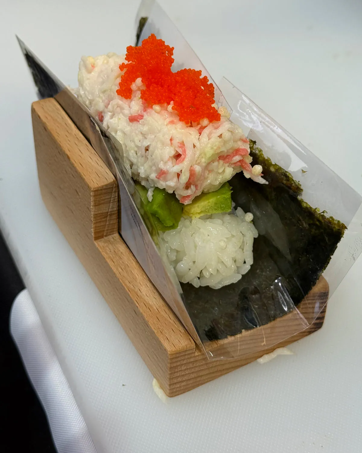 The finished California hand roll standing in its wooden holder