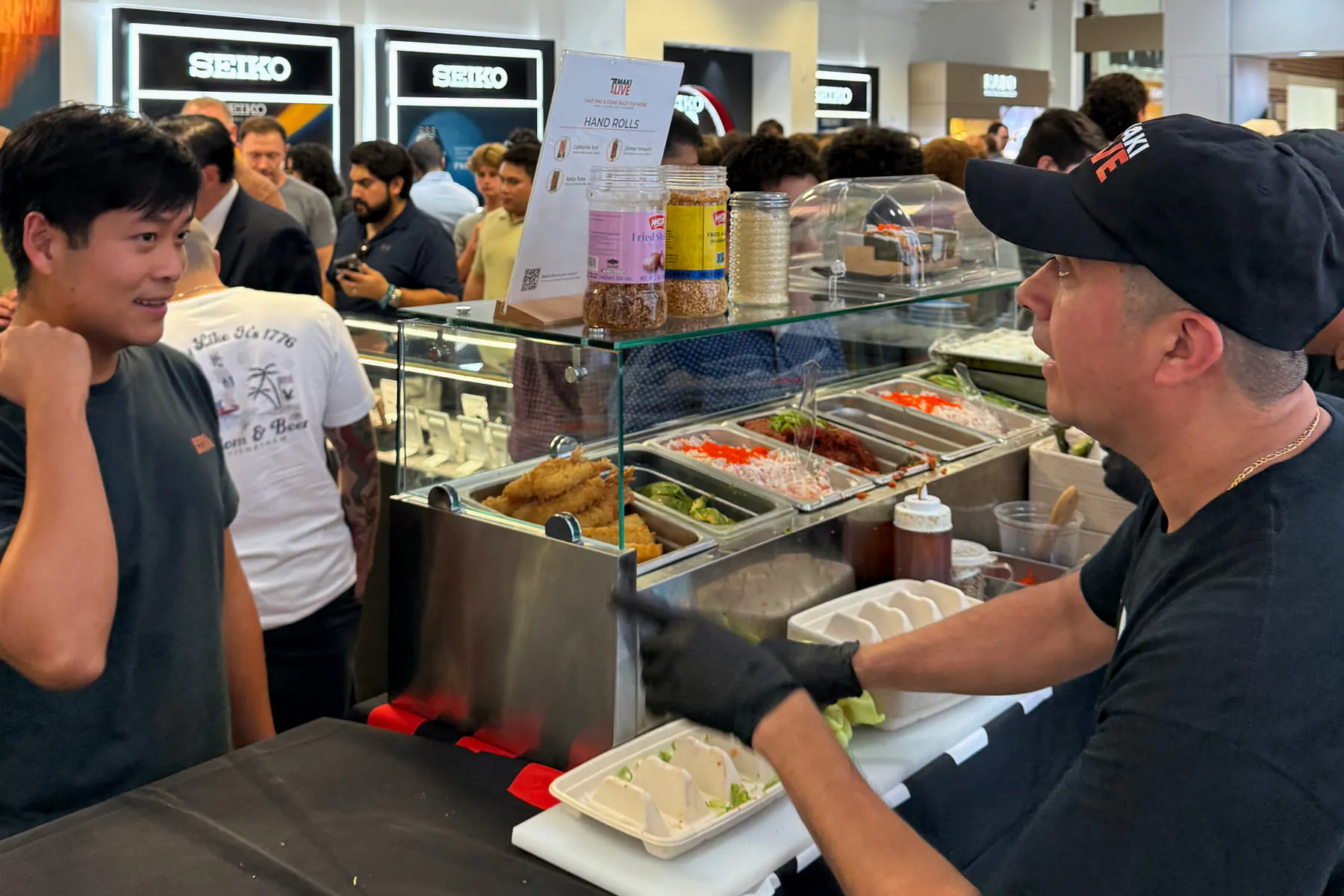 A chef handing a tray of hand rolls across the counter to a guest