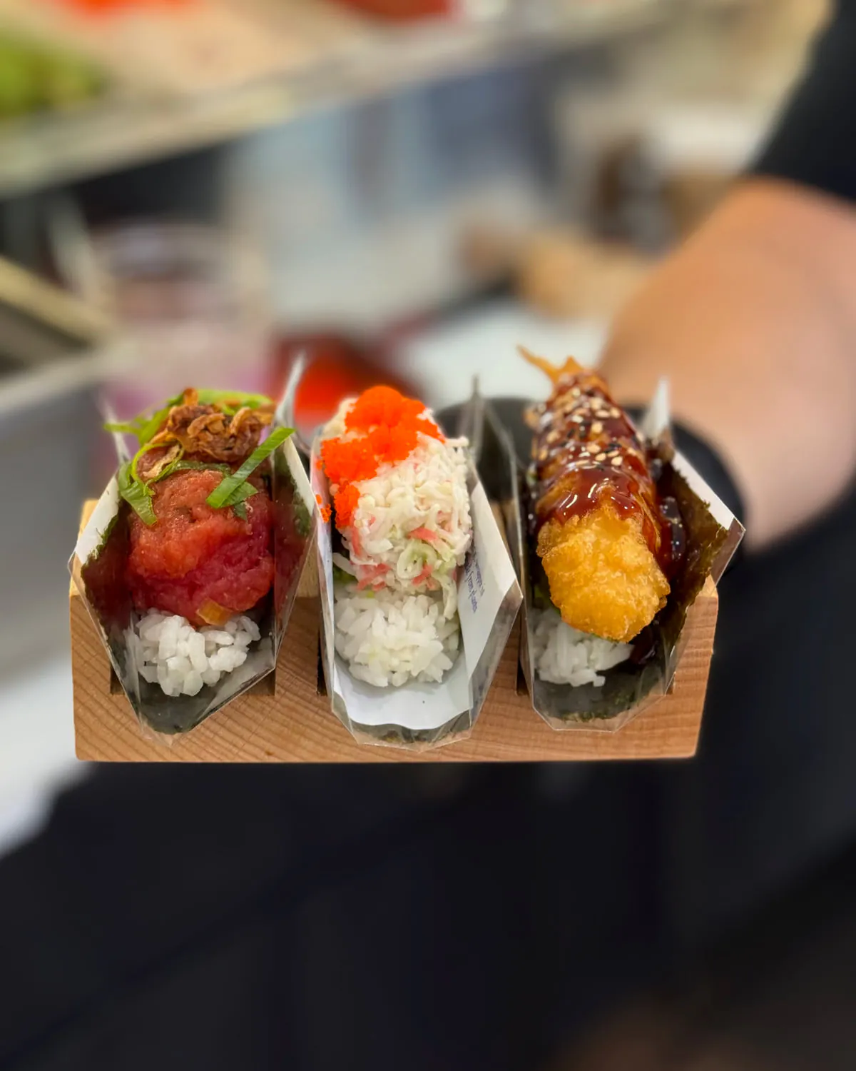 Three hand rolls in one wooden holder — spicy tuna, California and shrimp tempura