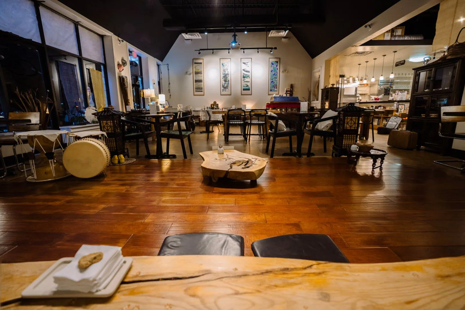 The main room at Soricha Tea & Theater, with wooden tables, scroll paintings and warm light