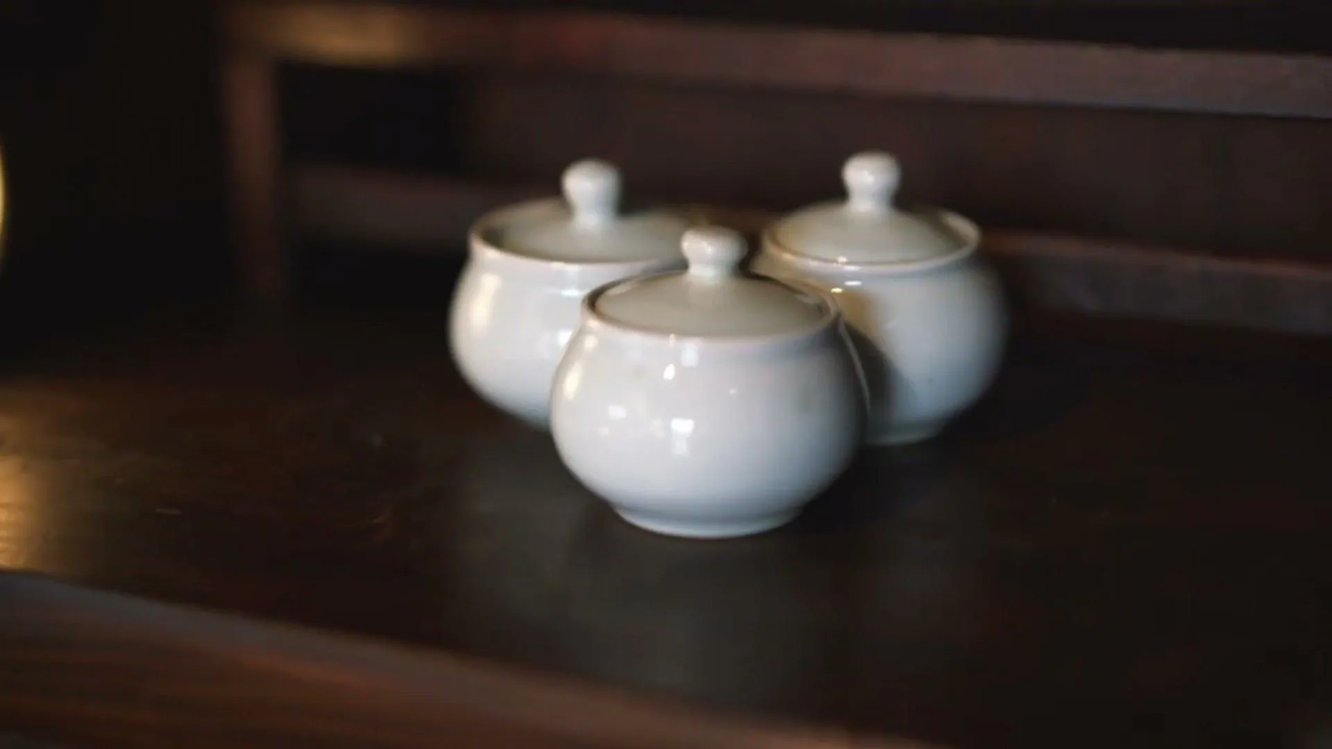 White ceramic teapots on a dark wooden shelf at Soricha