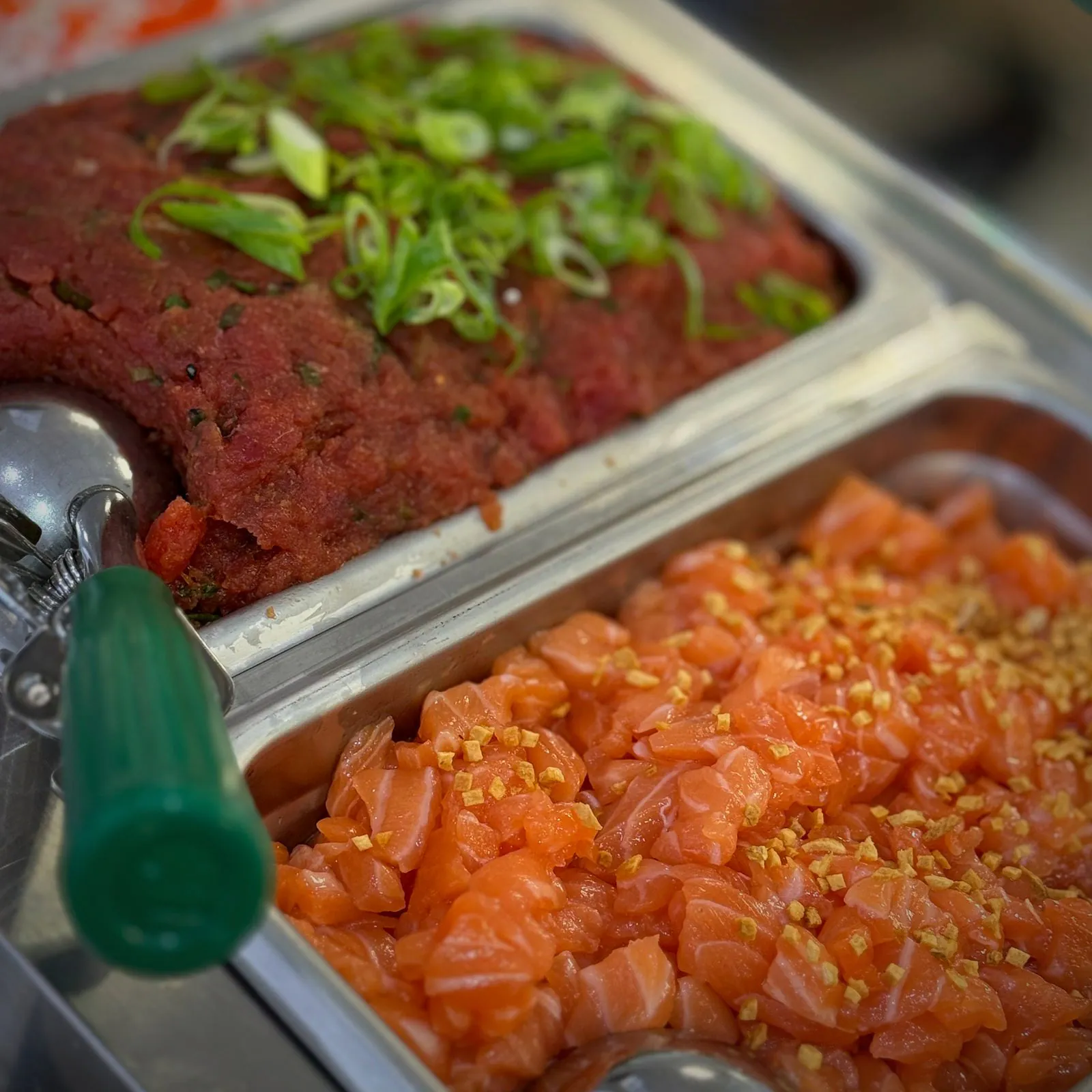 Spicy tuna topped with scallion and diced salmon with onion crunch in steel trays