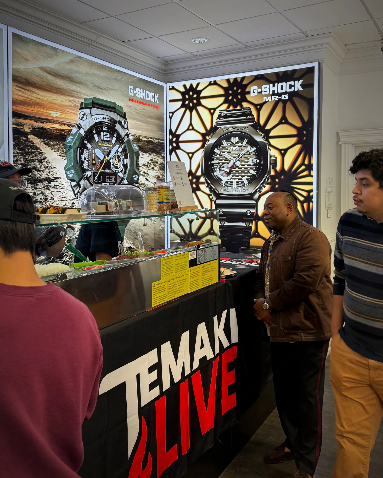 Guests standing at the Temaki Live counter in the showroom, watch displays behind