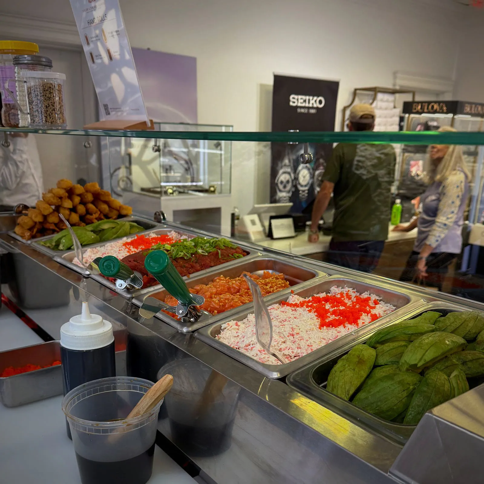 Trays of salmon, spicy tuna, crab, tobiko and avocado lined up behind the counter's glass
