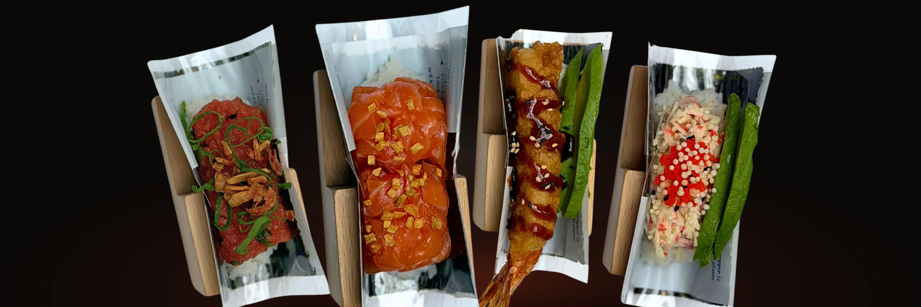 Four hand rolls standing in their wooden stands — spicy tuna, salmon, shrimp tempura and California