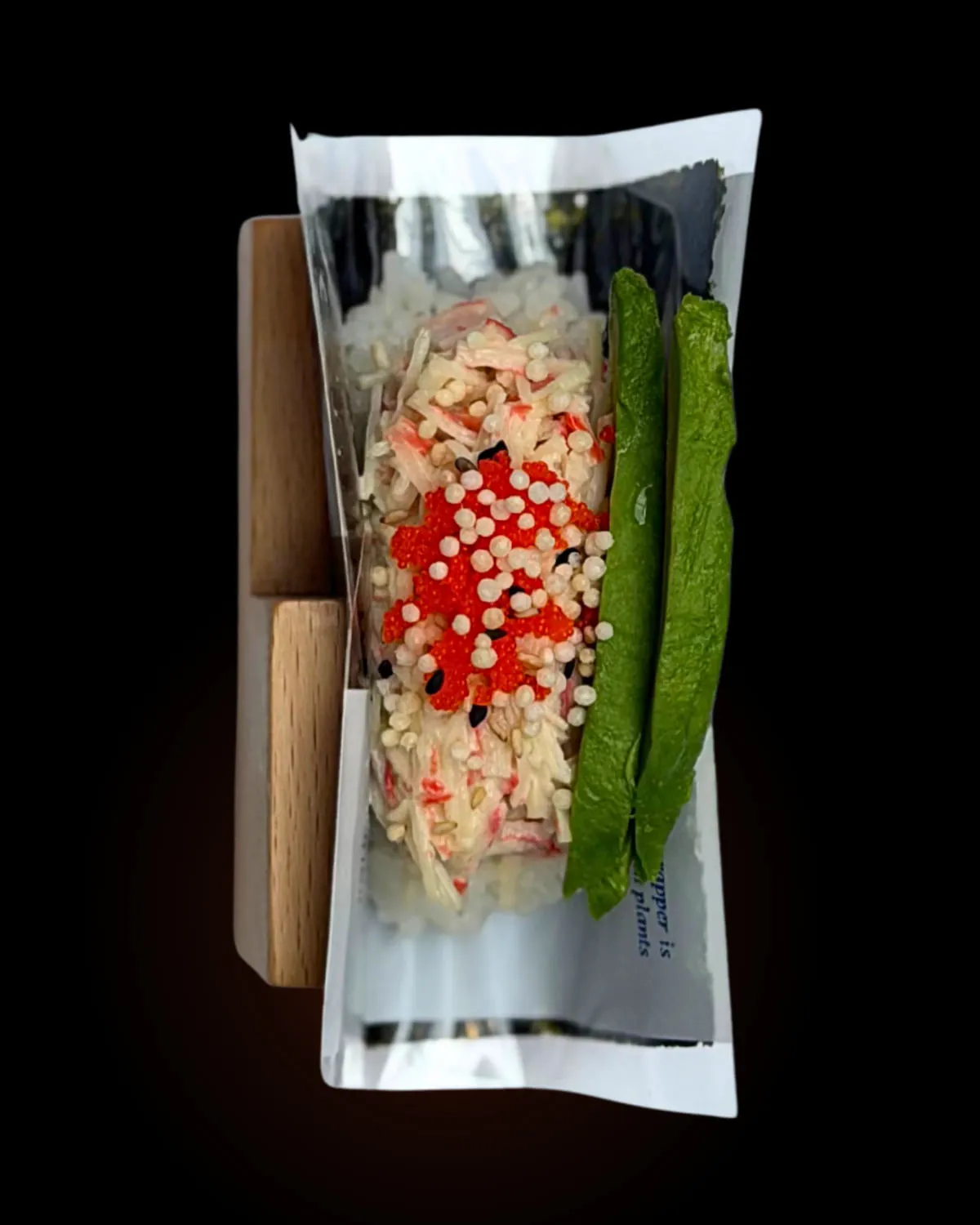A California hand roll in its stand against black